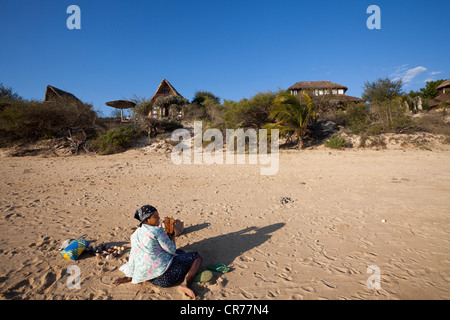 Malagasy woman selling sea shells on beach in front of chalets of Paradisier luxury hotel, Ifaty, Madagascar Stock Photo