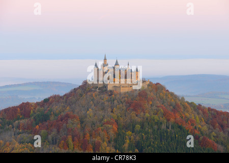 Burg Hohenzollern Castle in the early morning light with autumnal forest, early morning fog, Swabian Alb, Baden-Wuerttemberg Stock Photo