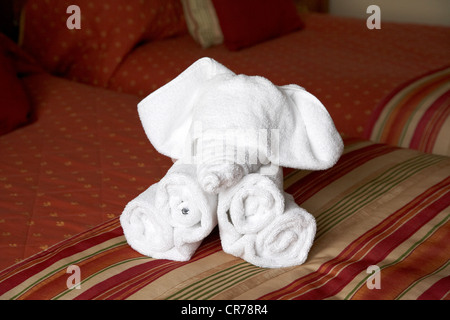 hotel towels folded into the shape of an elephant on a hotel bed in the uk Stock Photo