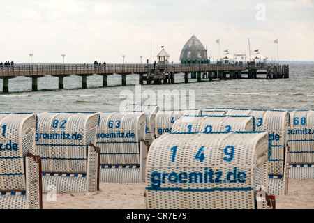 Roofed wicker beach chairs in front of Groemitz Pier, Baltic Sea resort town of Ostseebad Groemitz, Schleswig-Holstein Stock Photo