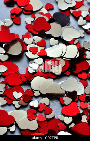 Red and silver heart confetti scattered on a cloth UK Stock Photo
