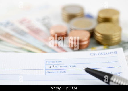 Receipt book, filled in with with VAT at 19%, with ball pen in front of euro notes and coins Stock Photo