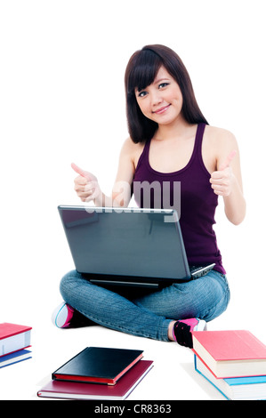 Attractive female student sitting on floor with laptop, giving thumbs up sign Stock Photo