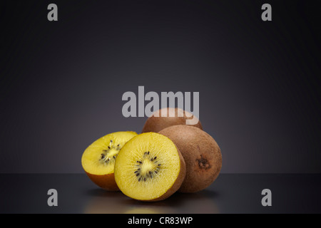 Kiwifruit or kiwi (Actinidia deliciosa) on a dark glass plate Stock Photo