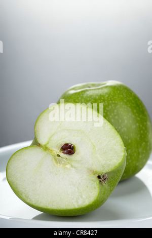 Two green Granny Smith apples, one whole apple and one apple cut in half Stock Photo