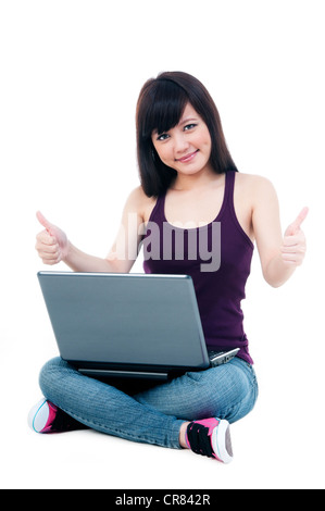 Attractive young female sitting on floor with laptop, giving thumbs up gesture Stock Photo