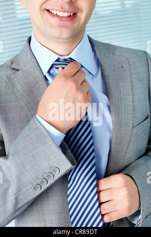 Smart businessman touching his necktie and smiling Stock Photo