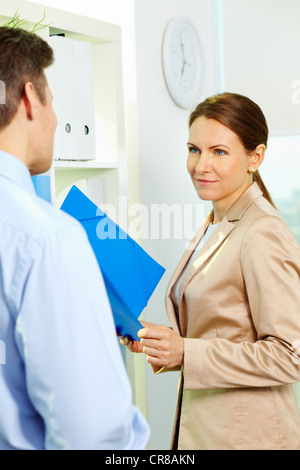 Formally dressed middle aged secretary listening to her boss Stock Photo