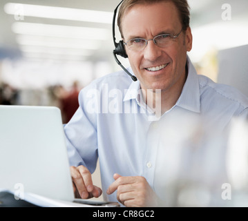 Businessman using laptop and wearing headset, portrait Stock Photo