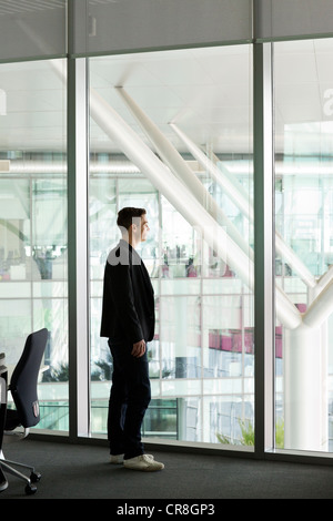 Young man looking out of window in IT office