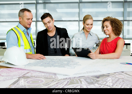 Engineer with architects looking at blueprints and digital tablet in office Stock Photo