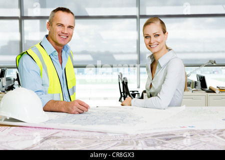 Portrait of engineer with architect at desk of blueprints in office Stock Photo