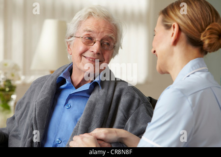 Carer touching senior mans hand Stock Photo
