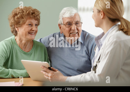 Doctor using digital tablet with senior couple Stock Photo