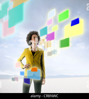 Businesswoman looking at holographic screens in desert Stock Photo