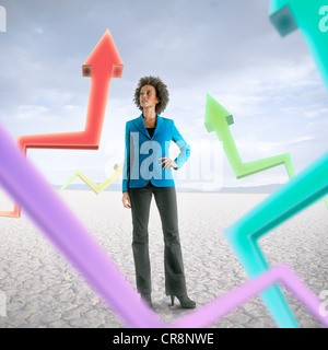 Businesswoman looking at holographic arrows in desert Stock Photo