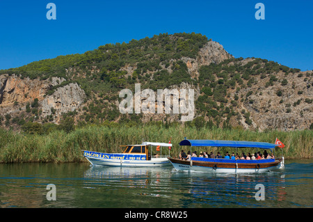 Excursion boats on the Dalyan river in front of the rock tombs of Caunos or Kaunos near Marmaris, Turkish Aegean Coast, Turkey Stock Photo
