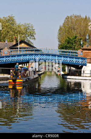 Barge houseboat narrow boat traveling under a blue bridge on the Grand Union canal London England Europe Stock Photo