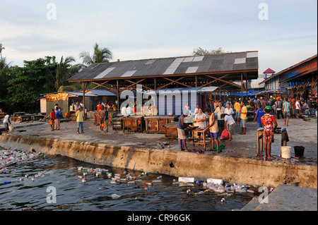 Papuans gutting fish that were bought at the fish market, floating plastic debris at front, Kota Biak, Biak Island, Irian Jaya Stock Photo