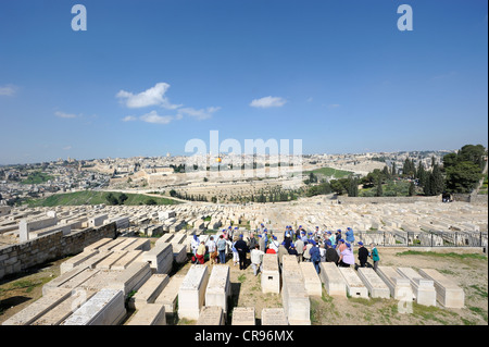 Group of tourists on a guided tour through the Jewish cemetery on the Mount of Olives overlooking the old town of Jerusalem Stock Photo