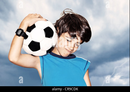 Football player celebrate victory, boy playing on stadium, enjoying game outdoor, sport fan portrait over cloudy sky background Stock Photo