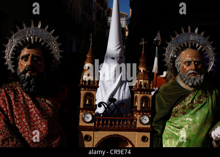 Masked men dressed as Saint Peter and Saint Paul hold a small scale church during an Easter Holy Week in Puente Genil, Spain Stock Photo