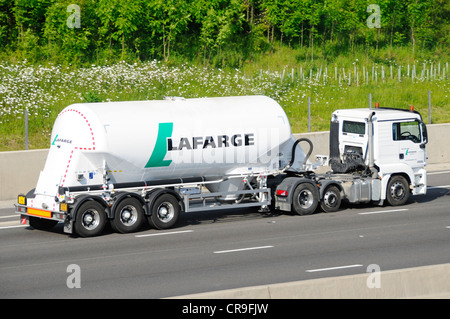 Side view LaFarge bulk cement powder carrier in articulated tanker trailer towed by white hgv lorry truck driving along M25 motorway Essex England UK Stock Photo