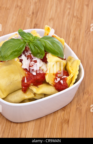 Bowl with fresh Raviolis on wooden background decorated with basil on top Stock Photo