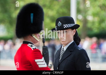 Female Metropolitan police officer in front of an Irish Guardsmen in the Mall for Trooping The Colour. The Mall, London, UK. Stock Photo