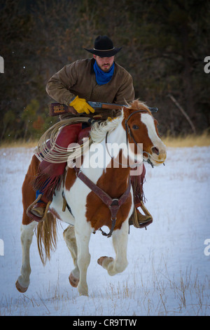 Cowboy and his horse riding through the snow on a ranch in northeastern Wyoming Stock Photo