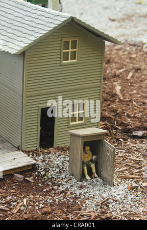 Man sitting in outhouse. Scene from a back yard Water Garden and Garden Train in Centerville, Dayton, Ohio, USA. Stock Photo