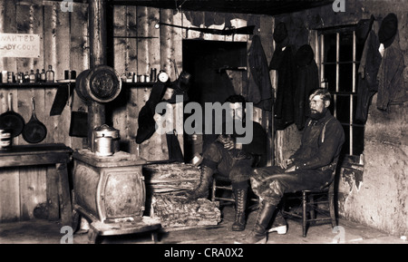 Two Men in Crude Cabin with Cat Stock Photo