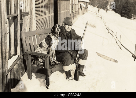 Older Hunter with Shotgun Sitting on Bench with his Hunting Dog Stock Photo