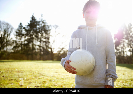 Boy carrying soccer ball in meadow Stock Photo