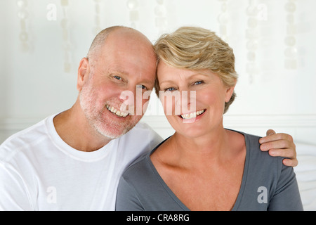 Smiling older couple sitting on bed Stock Photo