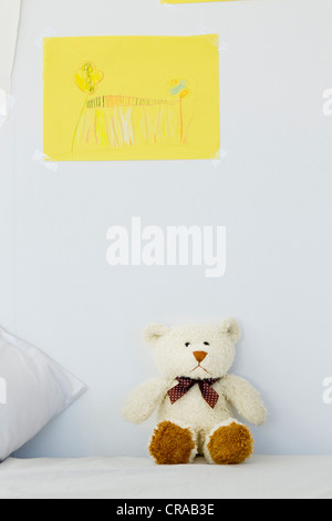 Teddy bear and childs drawing on bed Stock Photo