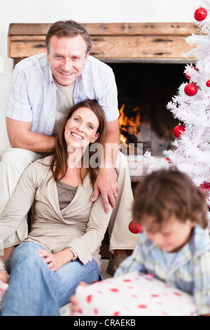Couple relaxing by Christmas tree Stock Photo