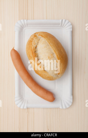 Roll with sausage on paper plate, fast food Stock Photo