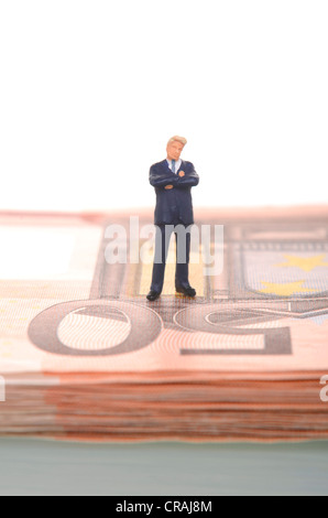Skeptical-looking businessman, figure standing on a stack of fifty euro banknotes