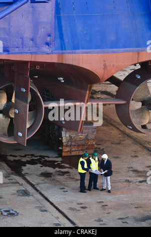 Workers reading blueprints at dry dock Stock Photo
