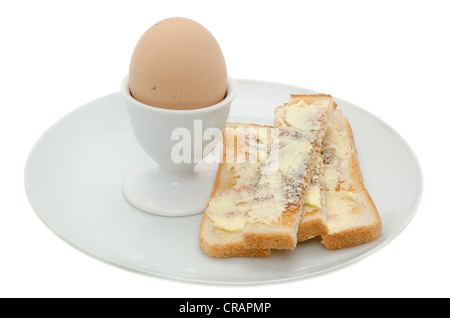 Freshly boiled egg in a white egg cup on a plate with toasted bread 'soldiers' or fingers Stock Photo