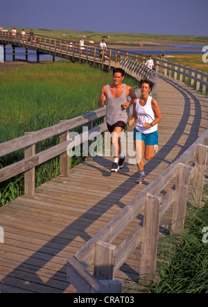 Young couple running on a boardwalk over  Kouchibouguac marsh. Stock Photo