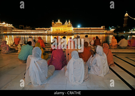 Praying Sikhs in front of the Sikh sanctuary Harmandir Sahib or Golden Temple in the Amrit Sagar, lake of nectar, Amritsar Stock Photo