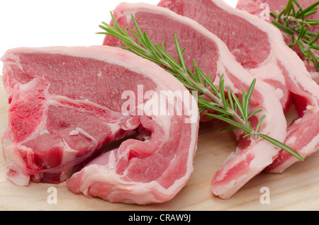 Close-up of four Lamb chops placed on a wooden cutting board - studio shot with a white background and medium depth of field Stock Photo
