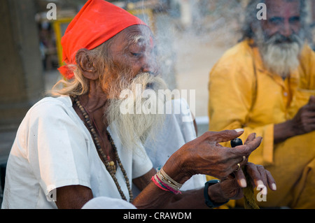 Sadhu with a white beard smoking Chillam, Maheshwar, Madhya Pradesh, India, Asia Stock Photo