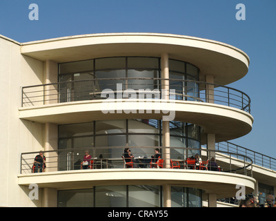 People relaxing on a semi circle balcony cafe in the sunshine, Bexhill Stock Photo
