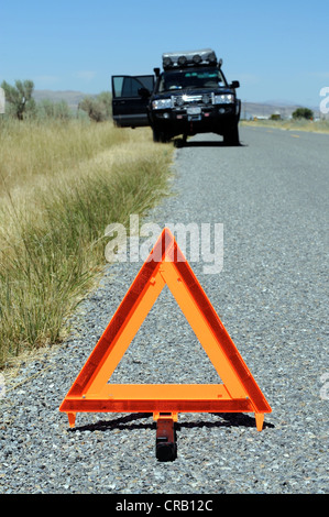 4x4 car broken down on road, with orange emergency warning triangle in foreground, US Stock Photo