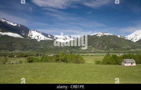 Small stone house in a mountain glade beneath snowy mountain in Bedous, Pyrenees-Atlantiques, France. Stock Photo