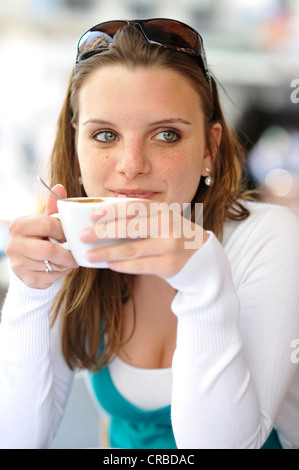 Young woman drinking coffee, holding coffee cup, cafe, Paris, France, Europe Stock Photo