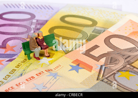 Miniature figurines of a retired couple sitting on a park bench on euro banknotes, symbolic image for retirement, pension Stock Photo